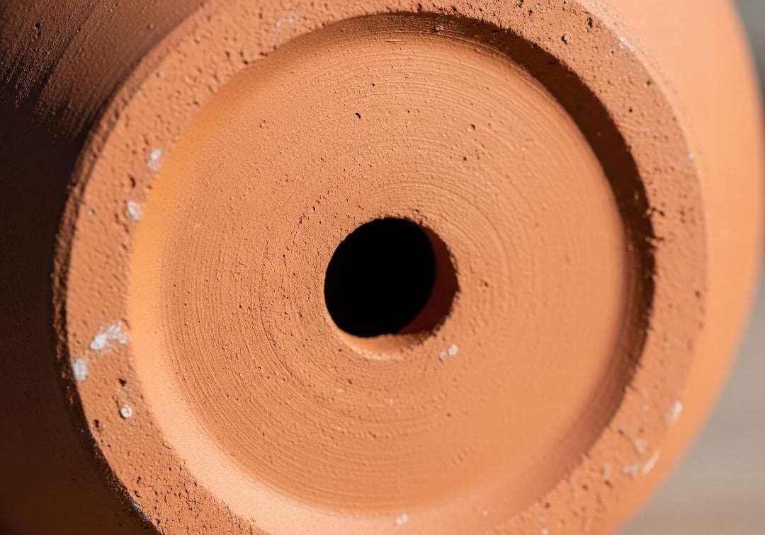 A close-up of the drainage hole at the bottom of a terracotta pot.